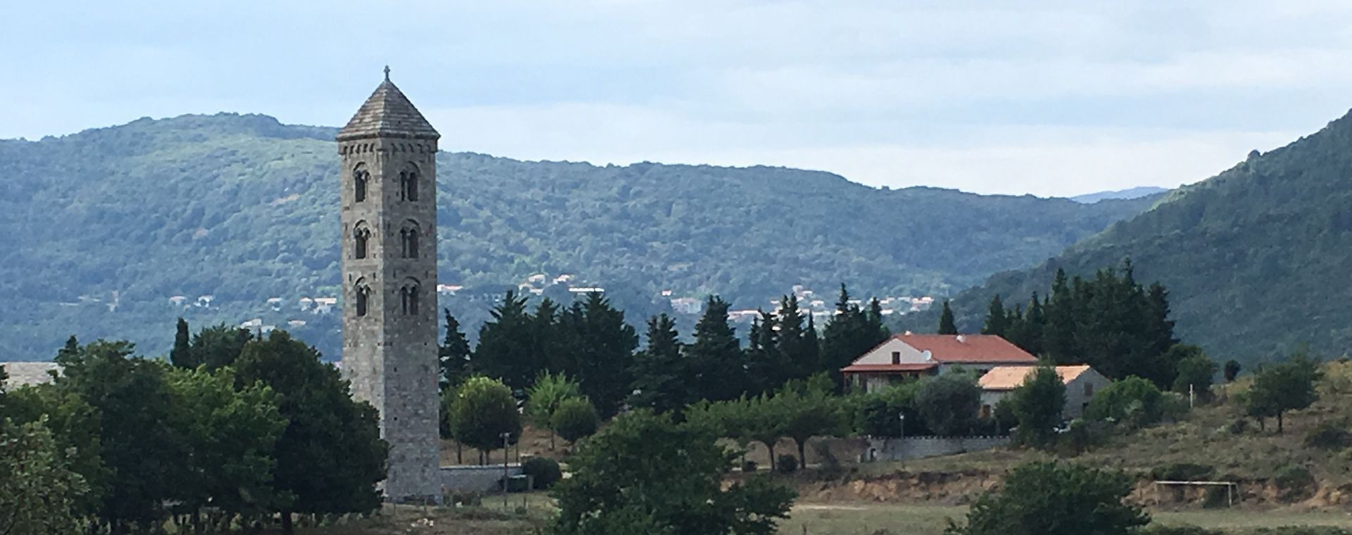 Clocher roman en pierre dans une vallée verdoyante - Corse, France