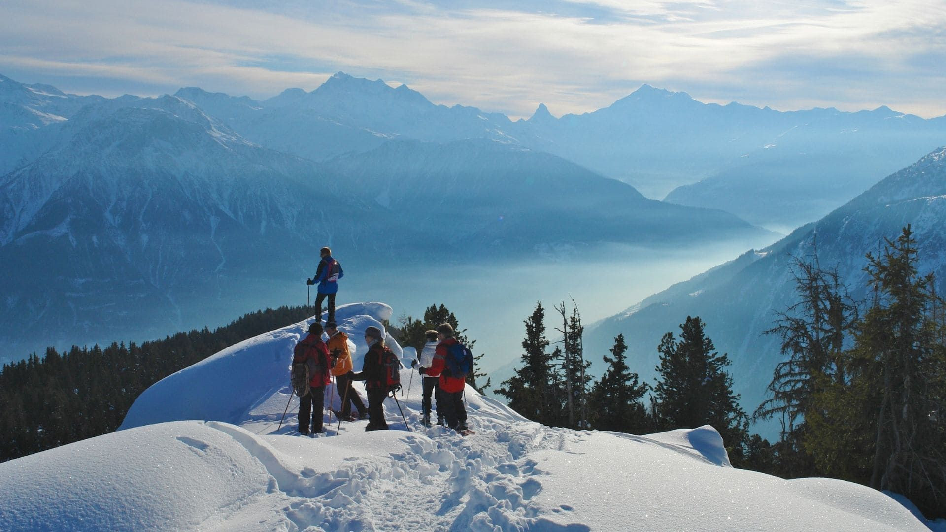 © Oriane Tempé Randonneurs en raquettes au-dessus de la vallée enneigée - Valais - Suisse