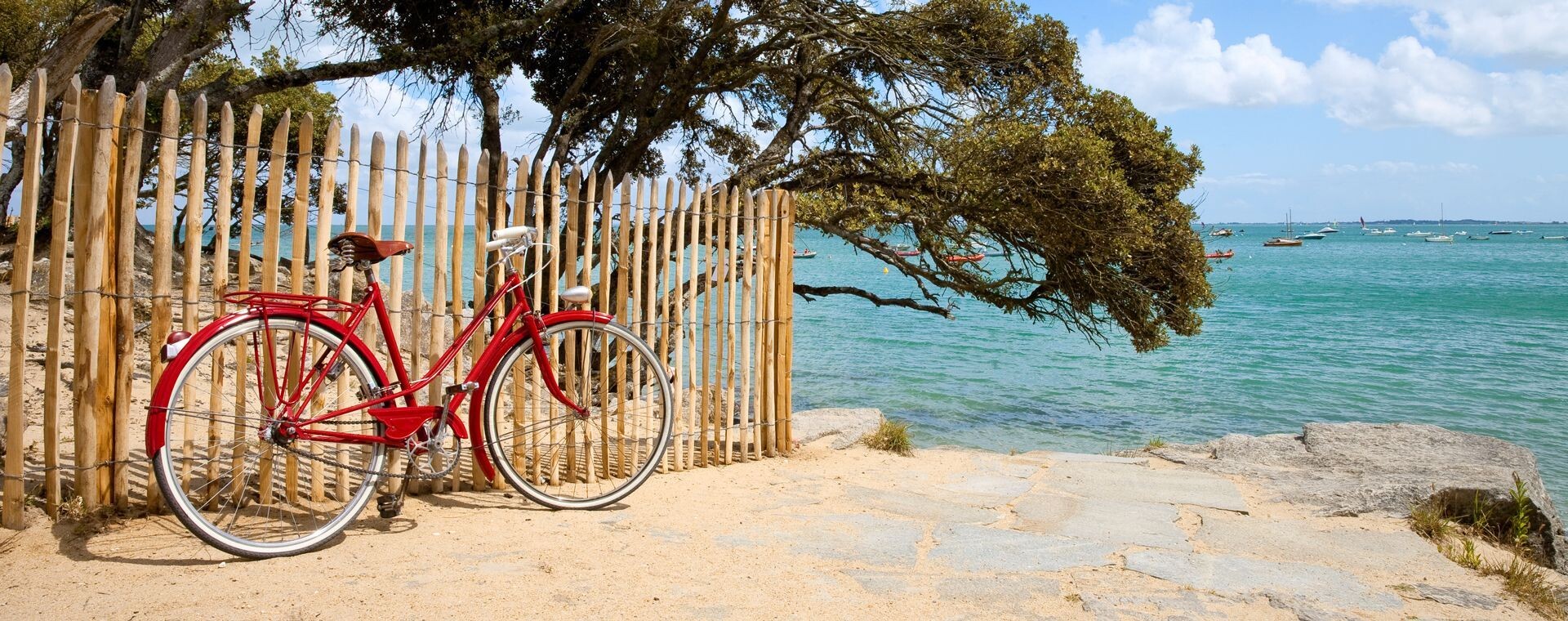 Vélo rouge contre une barrière en bord de mer - Île de Noirmoutier - Vendée, France