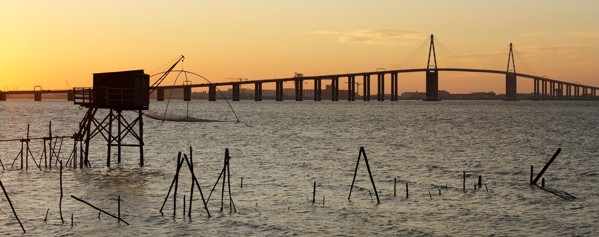 Carrelet de pêcheur et pont de Saint-Nazaire au coucher du soleil - France