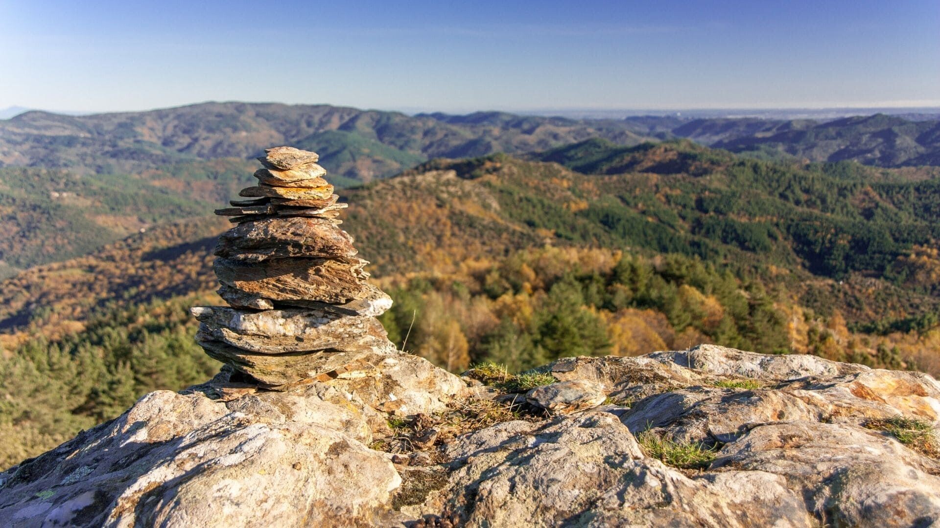 Cairn de pierres dominant les collines boisées - Cévennes - France