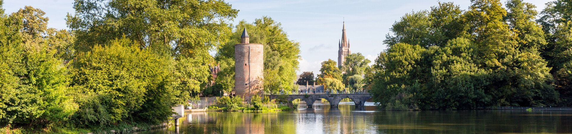 Canal avec tour médiévale et flèche d'église - Bruges - Belgique