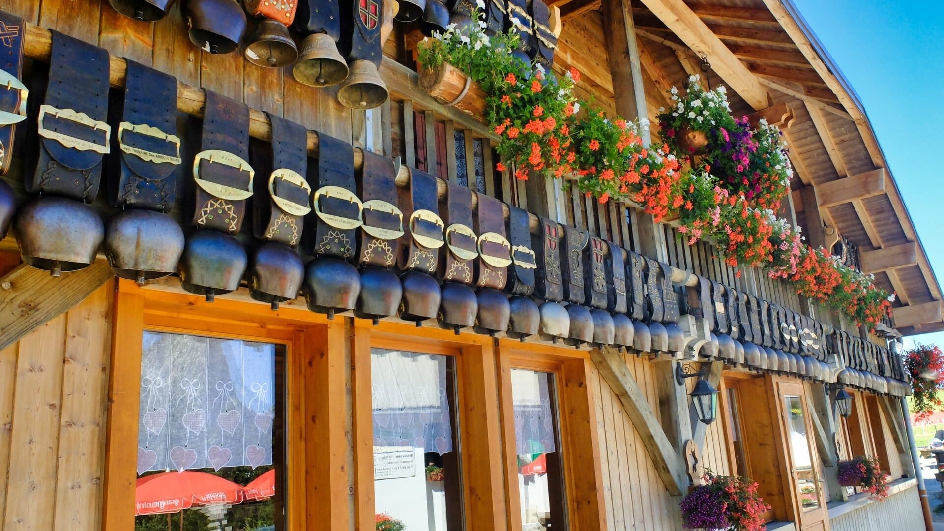 © Thomas Praire Façade de chalet ornée de cloches et géraniums - Aravis - France