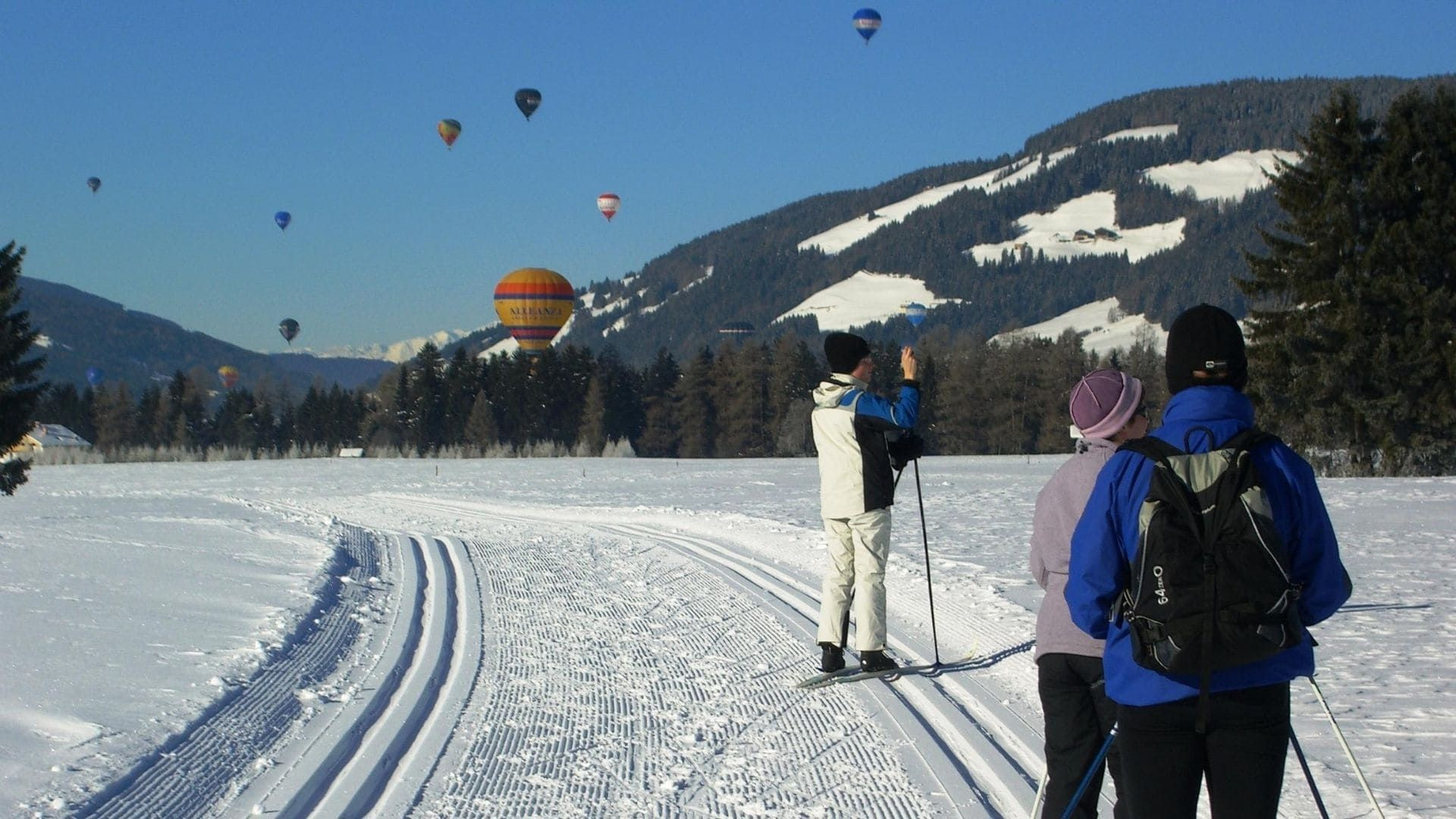 Skieurs de fond et montgolfières au-dessus de la vallée enneigée - Niederdorf - Dolomites