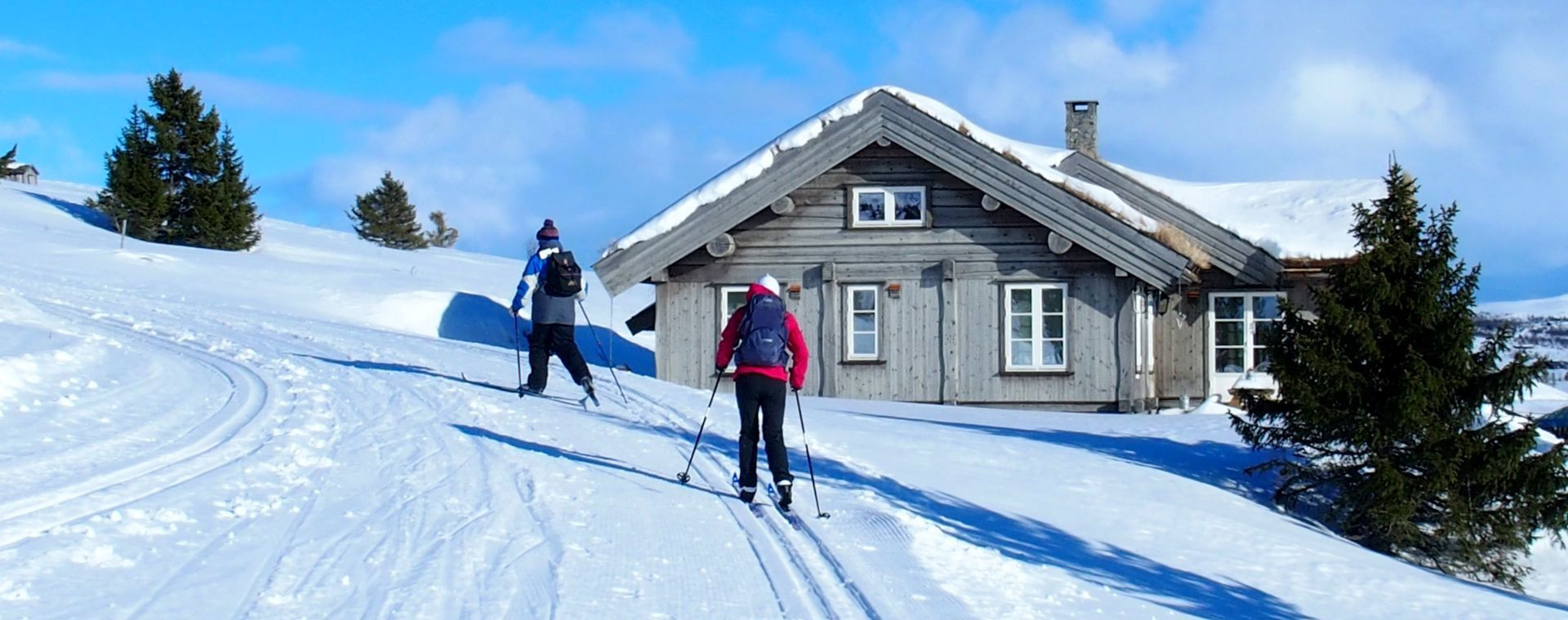 Skieurs de fond près d'un chalet en bois - Scandinavie