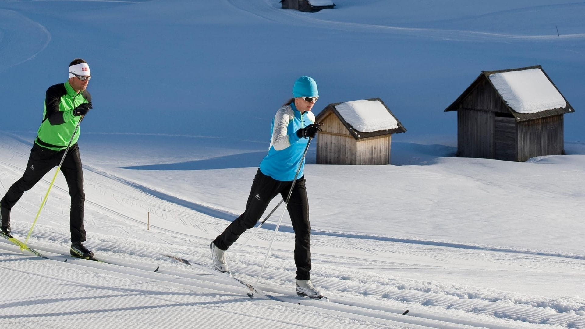 © T. Gruener Skieurs de fond sur piste damée près de granges en bois - Alpes