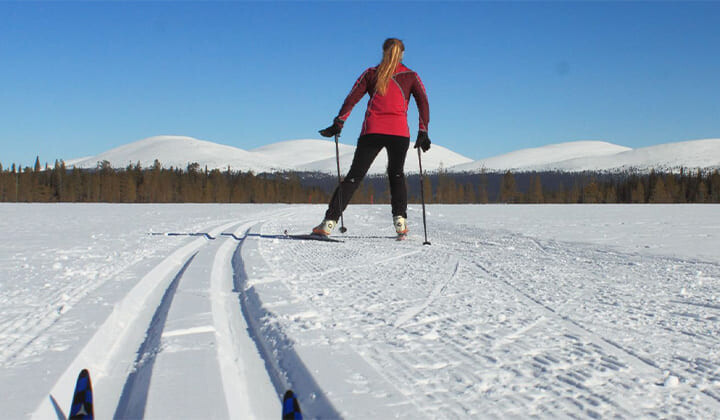 Skieuse de fond sur une piste tracée dans la plaine enneigée - Laponie - Finlande