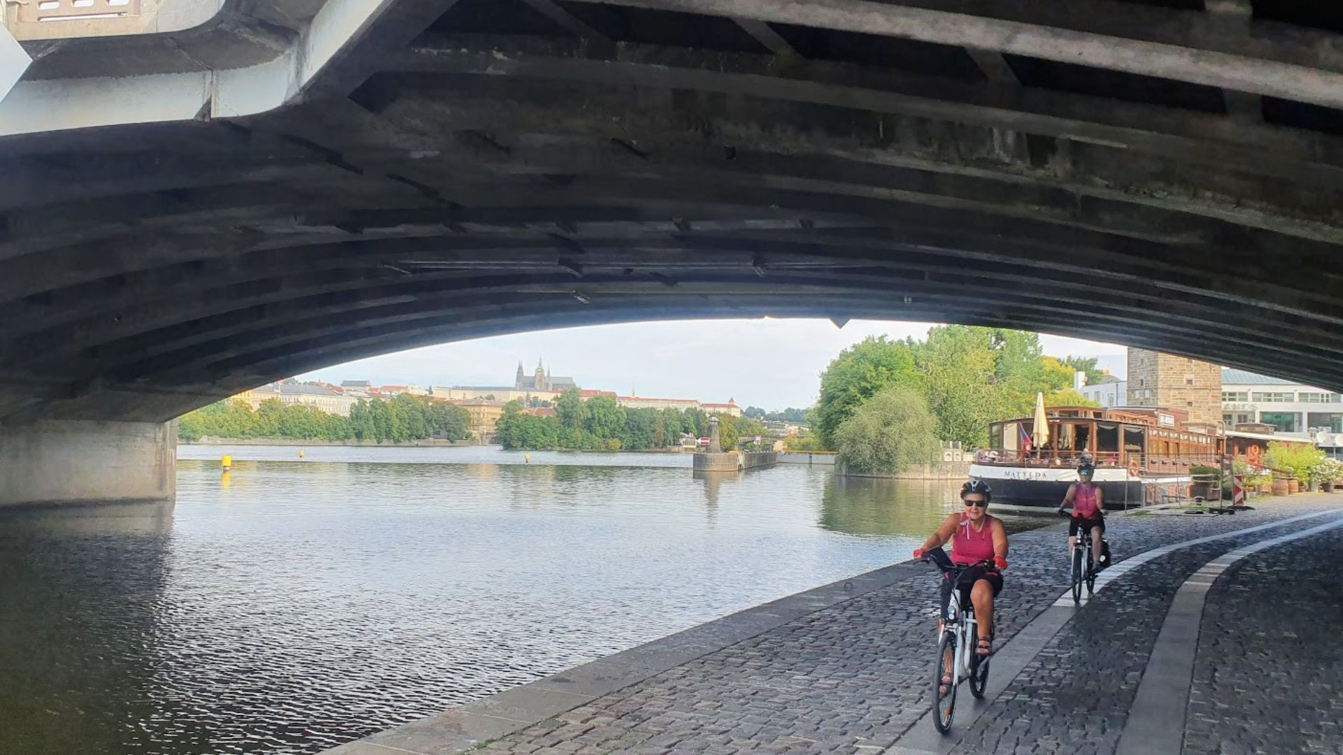 Cyclistes sur le quai de la Vltava sous le château de Prague - République tchèque