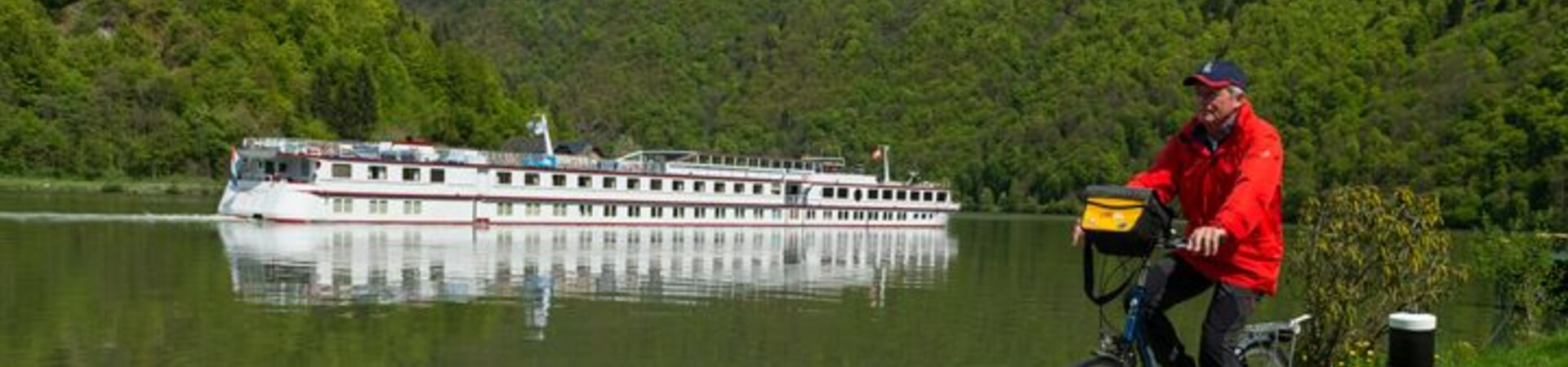 Cycliste sur la piste cyclable du Danube avec bateau de croisière - Danube - Europe