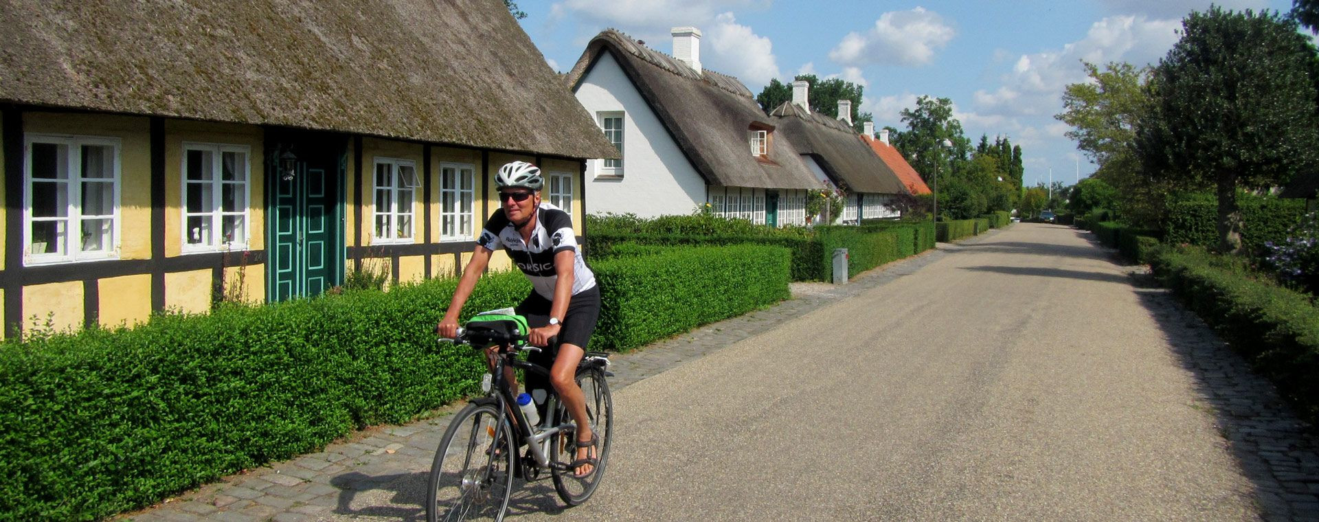 Cycliste devant maisons à colombages aux toits de chaume - Village danois - Danemark