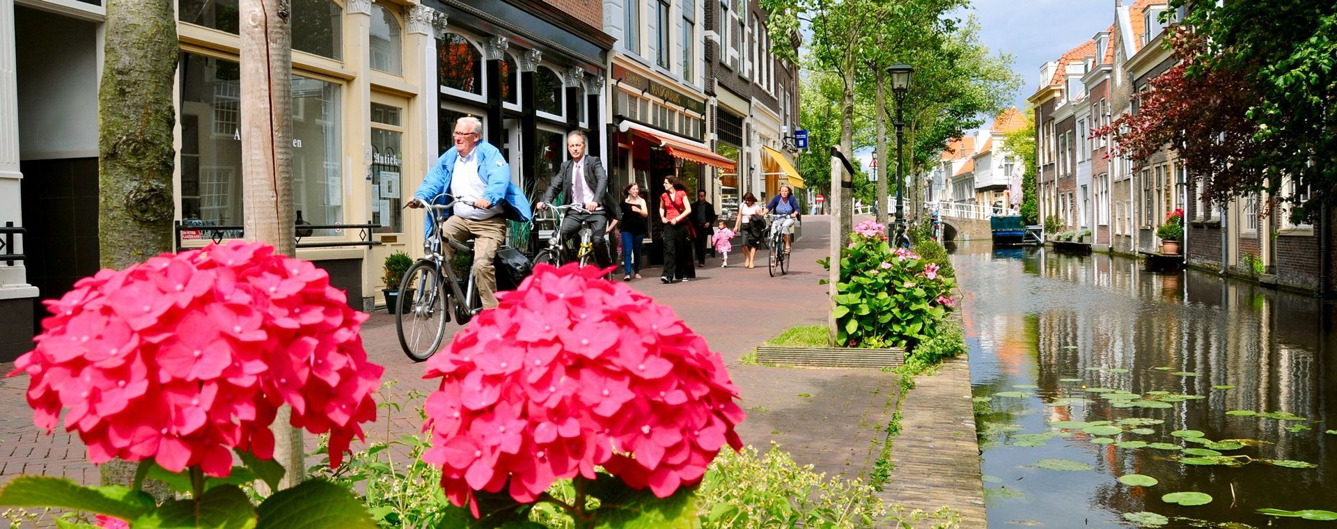 Cyclistes le long d'un canal fleuri au centre de Delft - Pays-Bas
