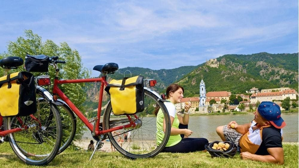 Cyclistes en pause pique-nique au bord du Danube face à Dürnstein - Wachau - Autriche