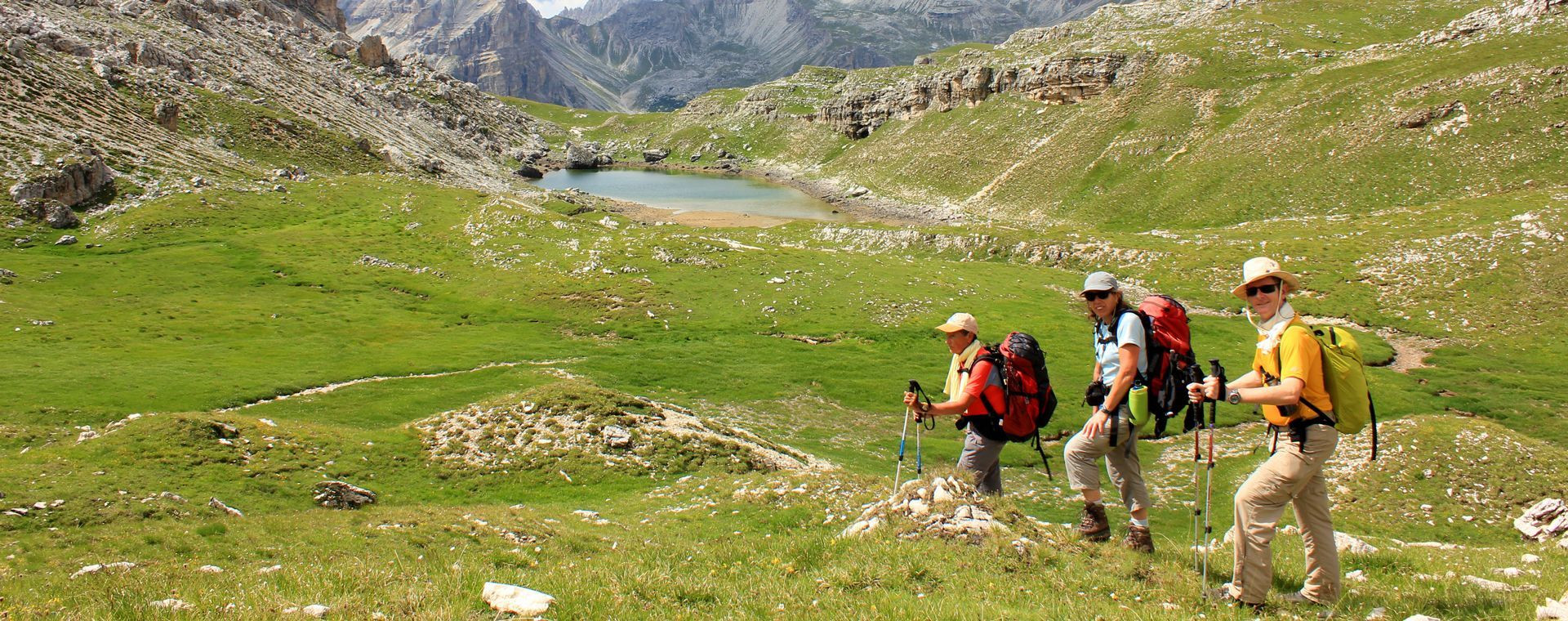 Randonneurs sur un alpage devant un lac - Dolomites - Italie