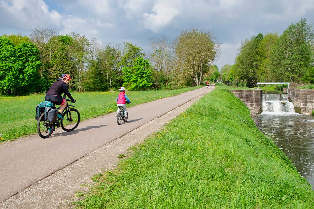 © Quentin Vanaker Famille à vélo le long du canal et de son écluse - Alsace - France
