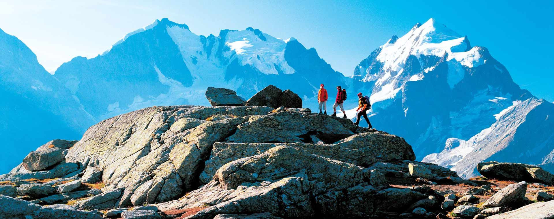 Randonneurs sur des rochers face aux sommets enneigés - Engadine - Suisse