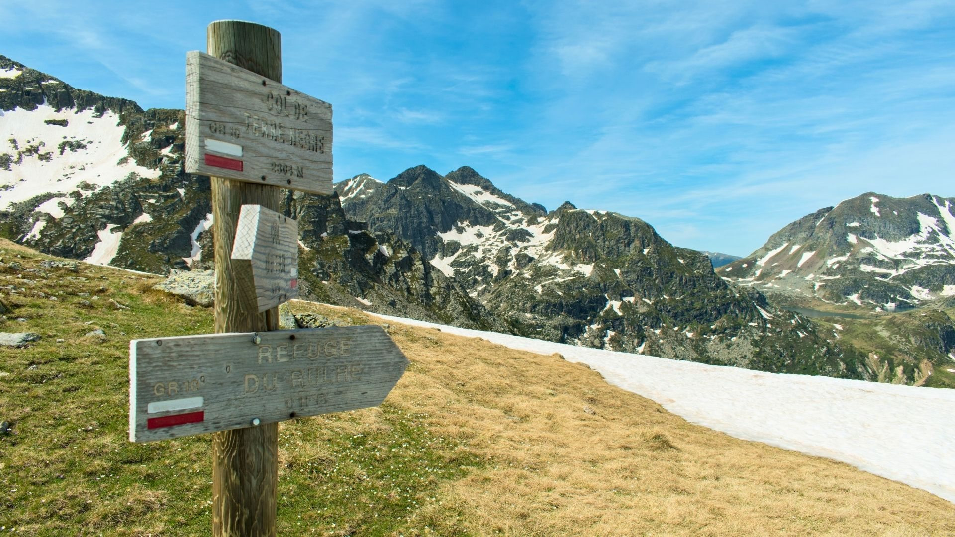 Waymarked GR signpost facing the snow-capped peaks of the Pyrenees