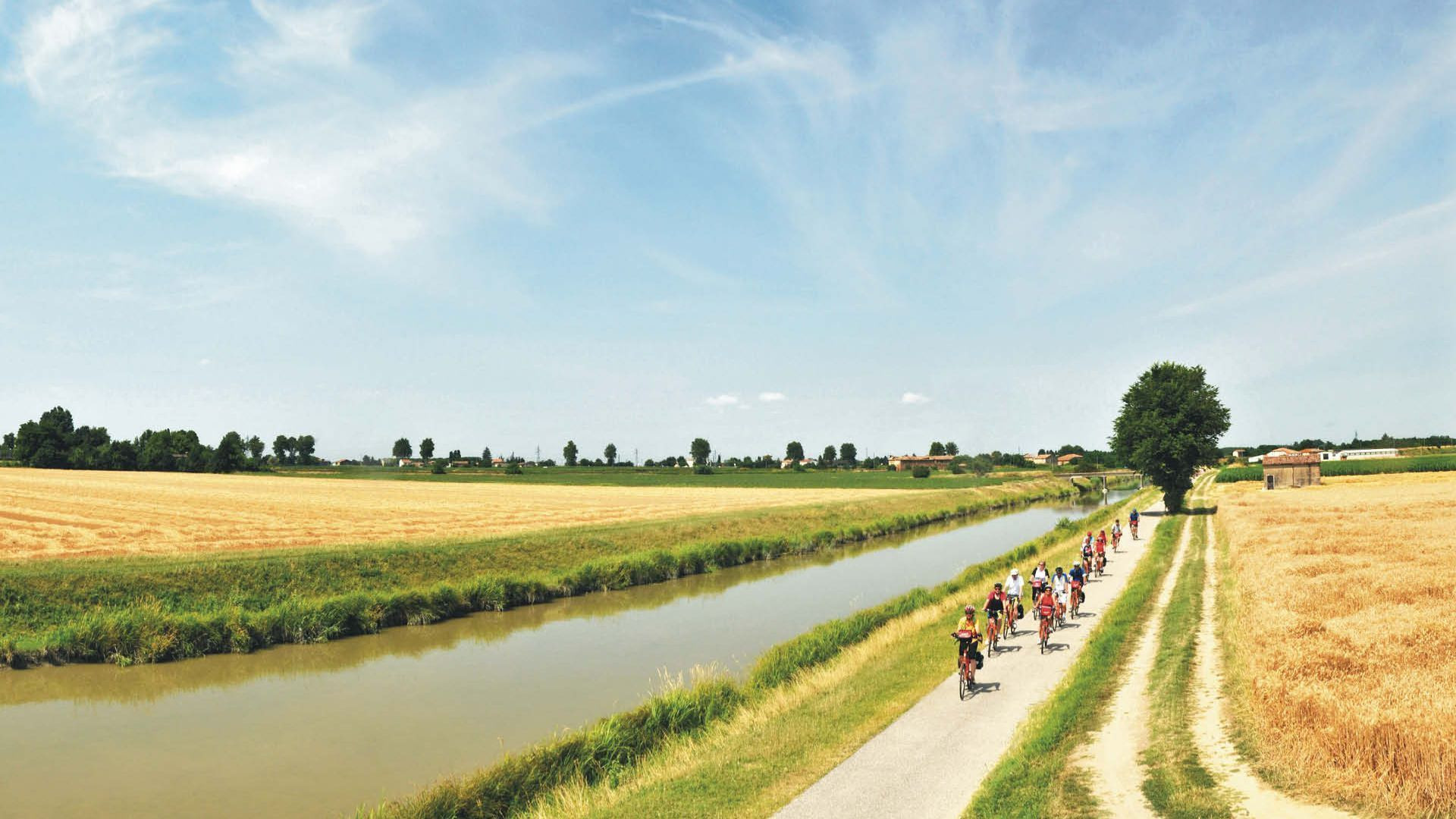 Cyclistes le long d'un canal dans la plaine du Pô - Vénétie - Italie