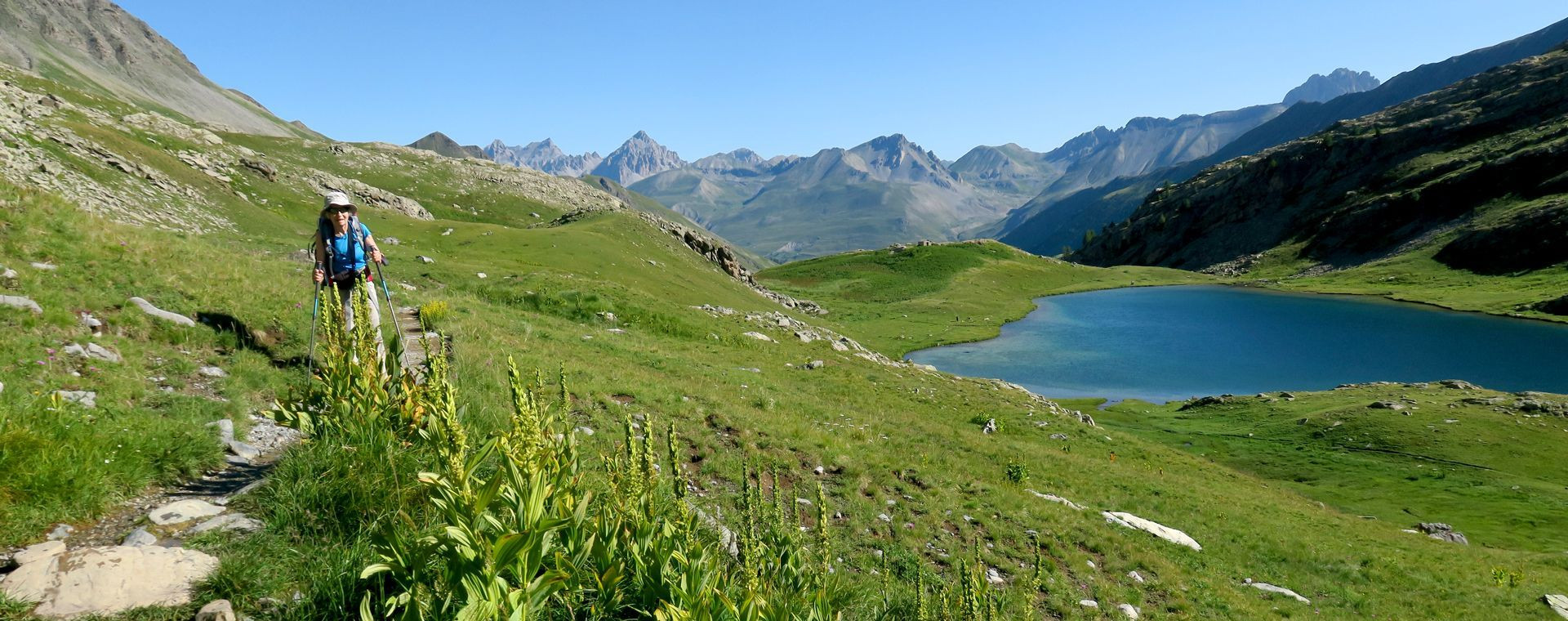 Randonneuse sur un sentier au-dessus d'un lac d'altitude - Alpes - France