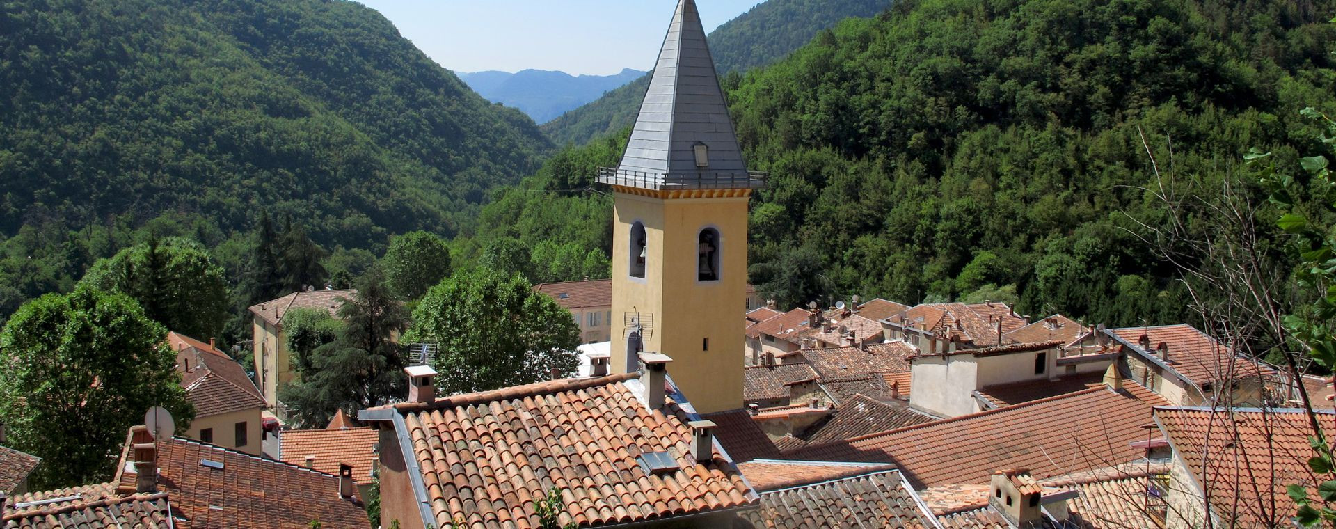 Village perché et clocher dans une vallée boisée - Alpes - France