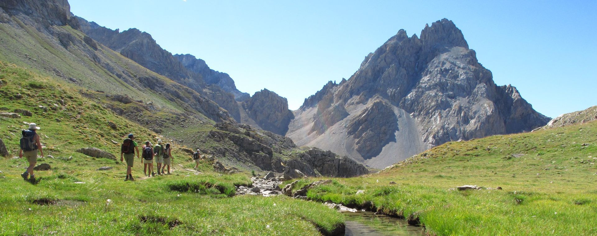 Randonneurs dans une vallée glaciaire vers un sommet - Alpes - France