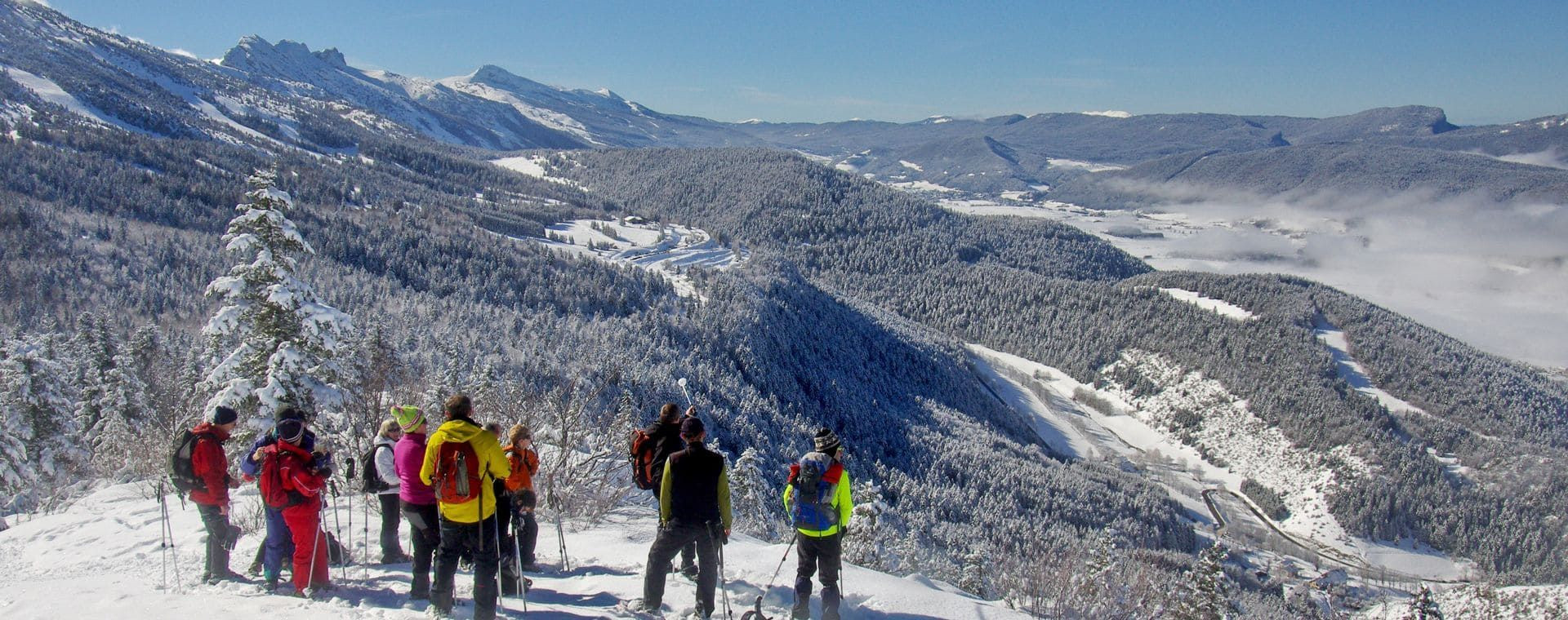 Groupe de randonneurs en raquettes devant le massif enneigé - Vercors - France