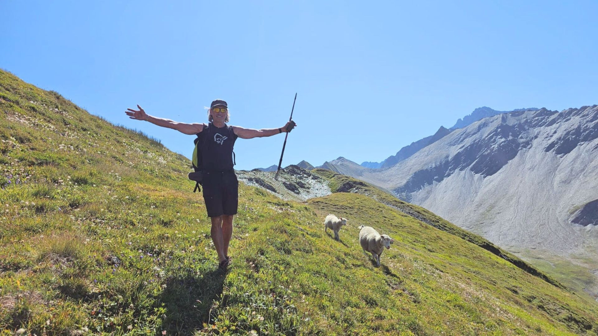 Randonneuse bras ouverts suivie de moutons - Tour du Mont-Blanc - France
