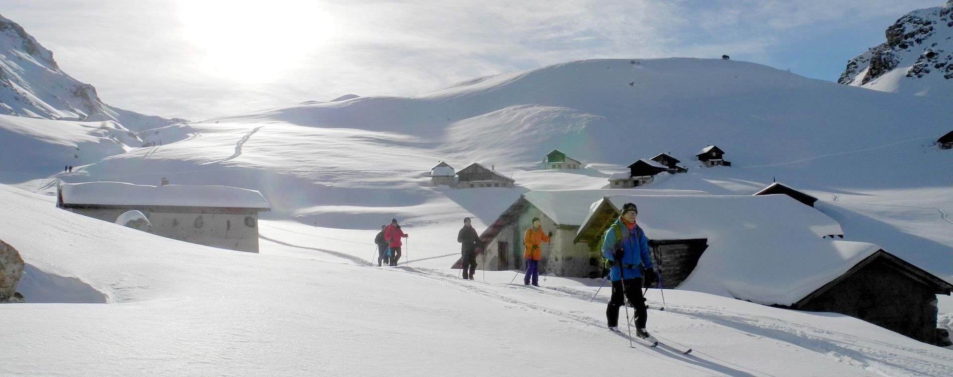 Groupe en ski de randonnée vers un hameau enneigé - Haute Ubaye - France