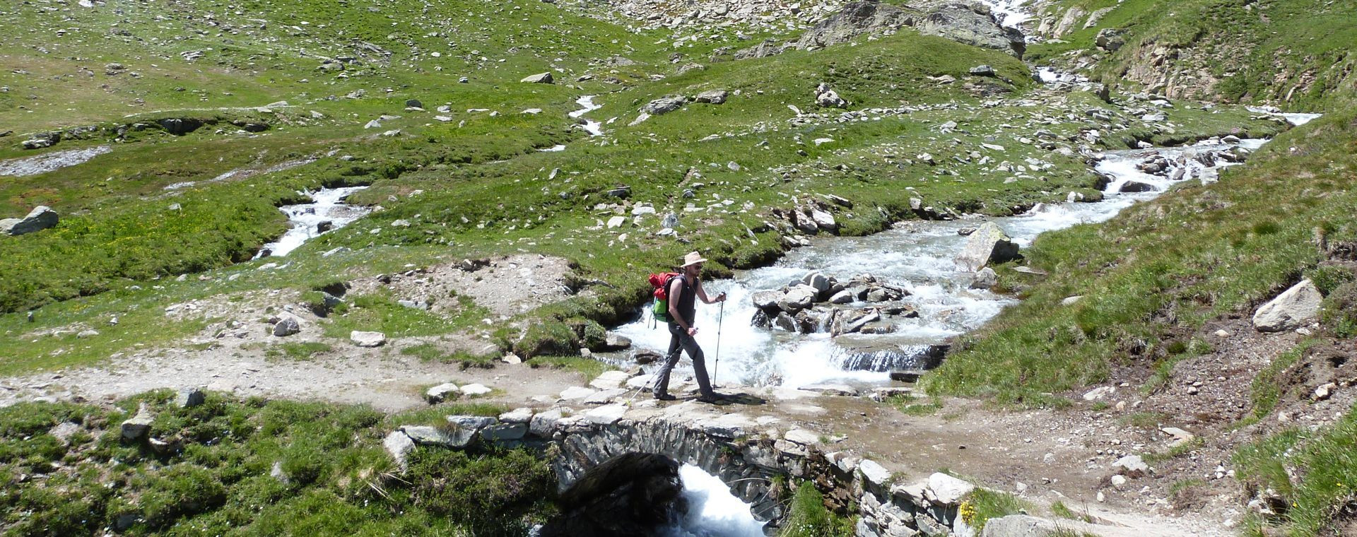 Randonneur franchissant un pont sur un torrent de montagne - Alpes du Nord - France