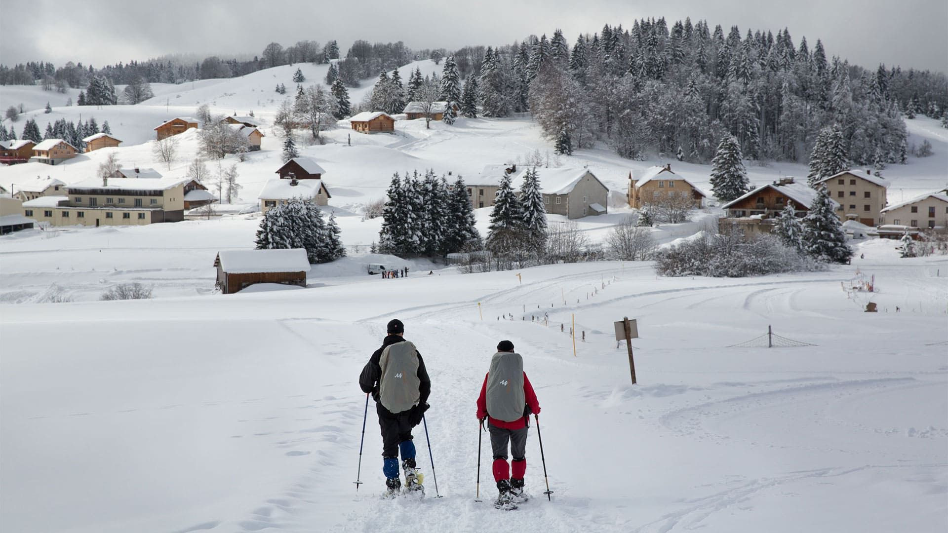 Randonneurs en raquettes au-dessus d'un village - Grande Traversée du Jura - France