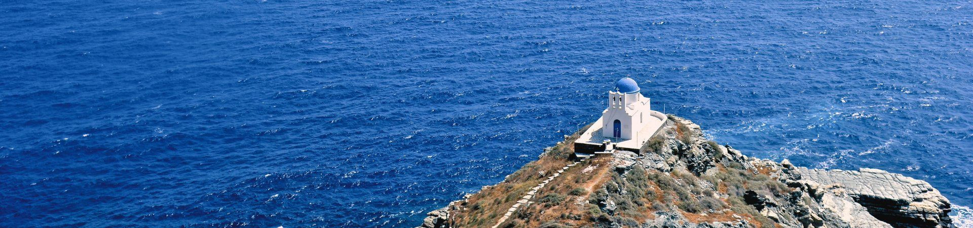 Chapelle blanche sur un promontoire au-dessus de la mer Égée - Grèce