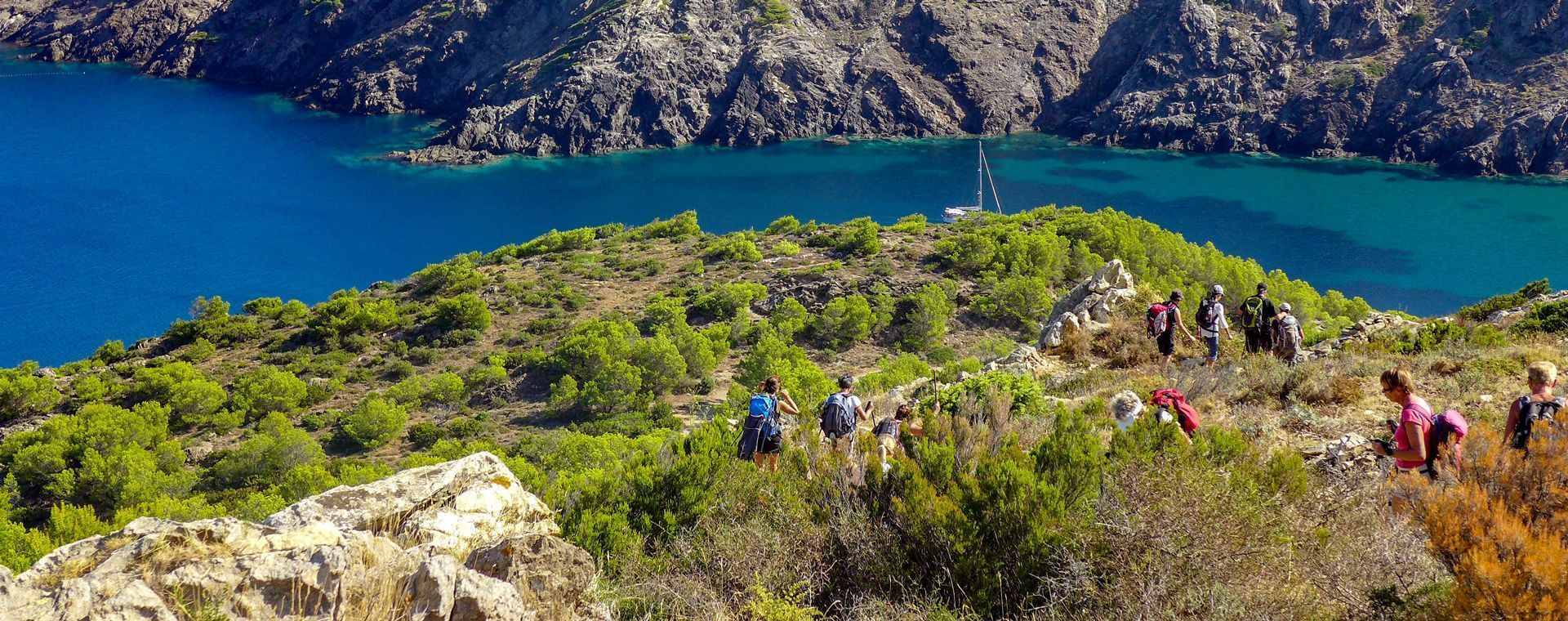 Randonneurs sur un sentier côtier surplombant une crique turquoise - Costa Brava - Espagne