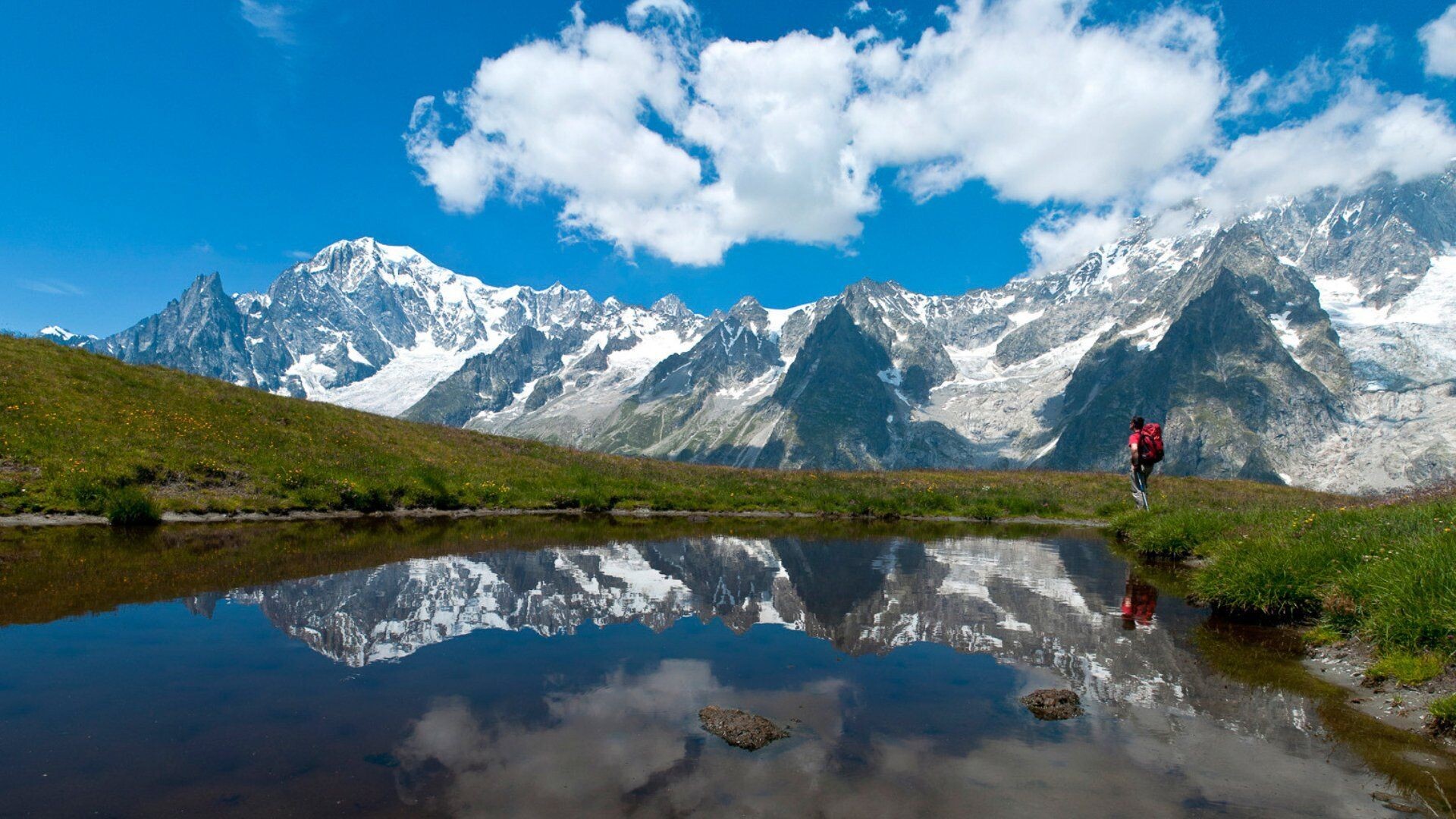 Randonneur au bord d'un lac d'altitude reflétant le massif du Mont-Blanc - Alpes