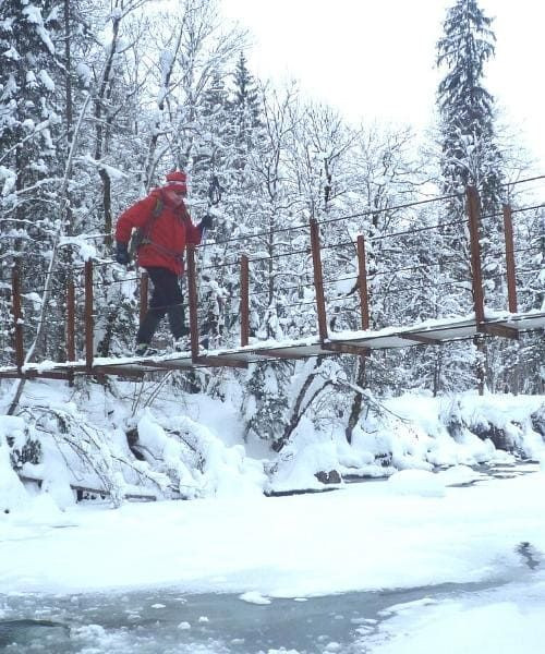 Randonneur traversant un pont enneigé sur la rivière Subersach - Vorarlberg - Autriche