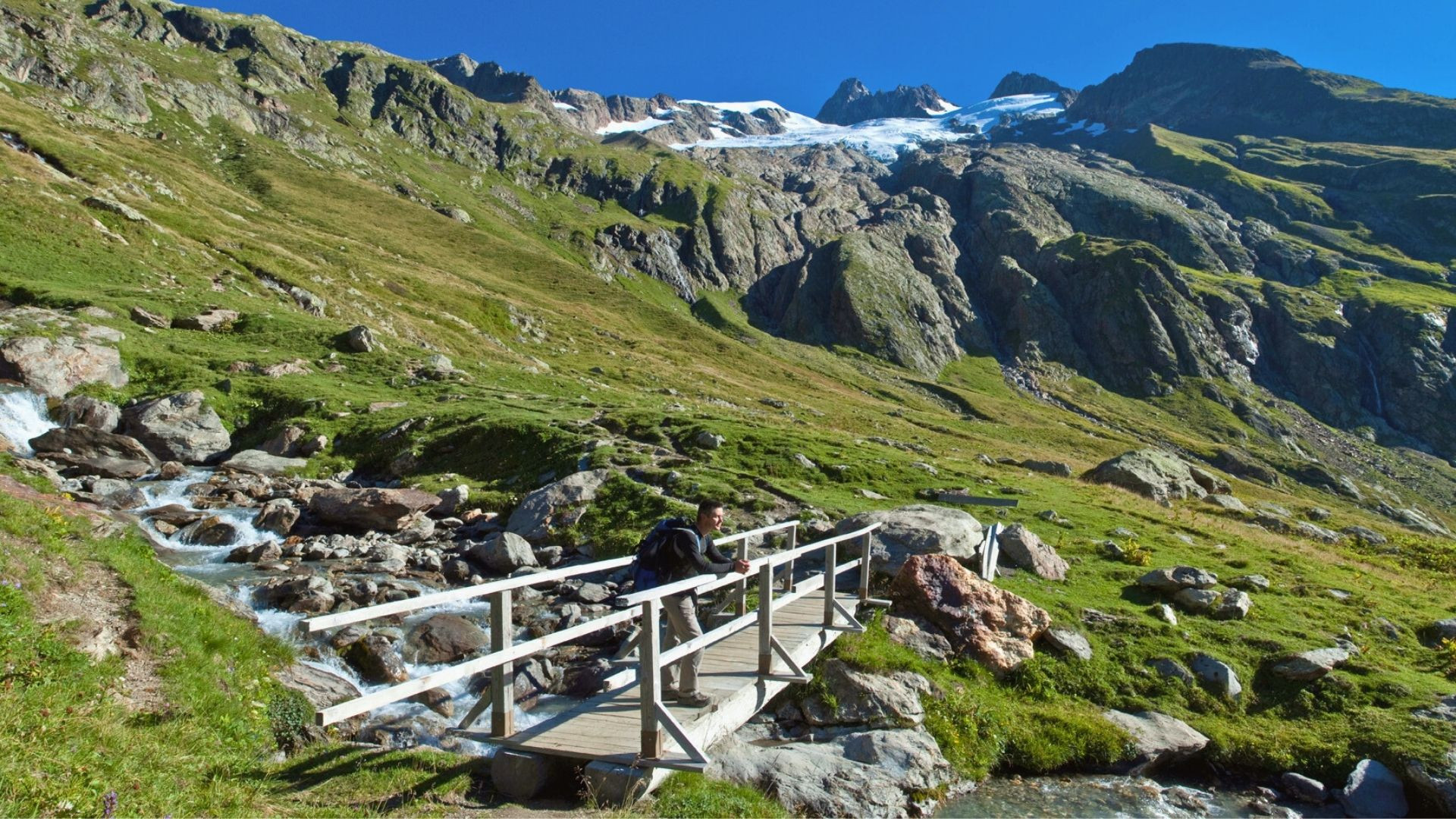 Randonneur traversant un pont de bois près d'un glacier - Massif du Mont-Blanc - France