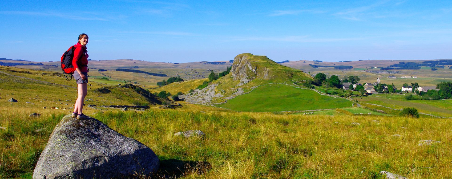 Randonneur sur un rocher dominant les plateaux de l'Aubrac - Massif central - France