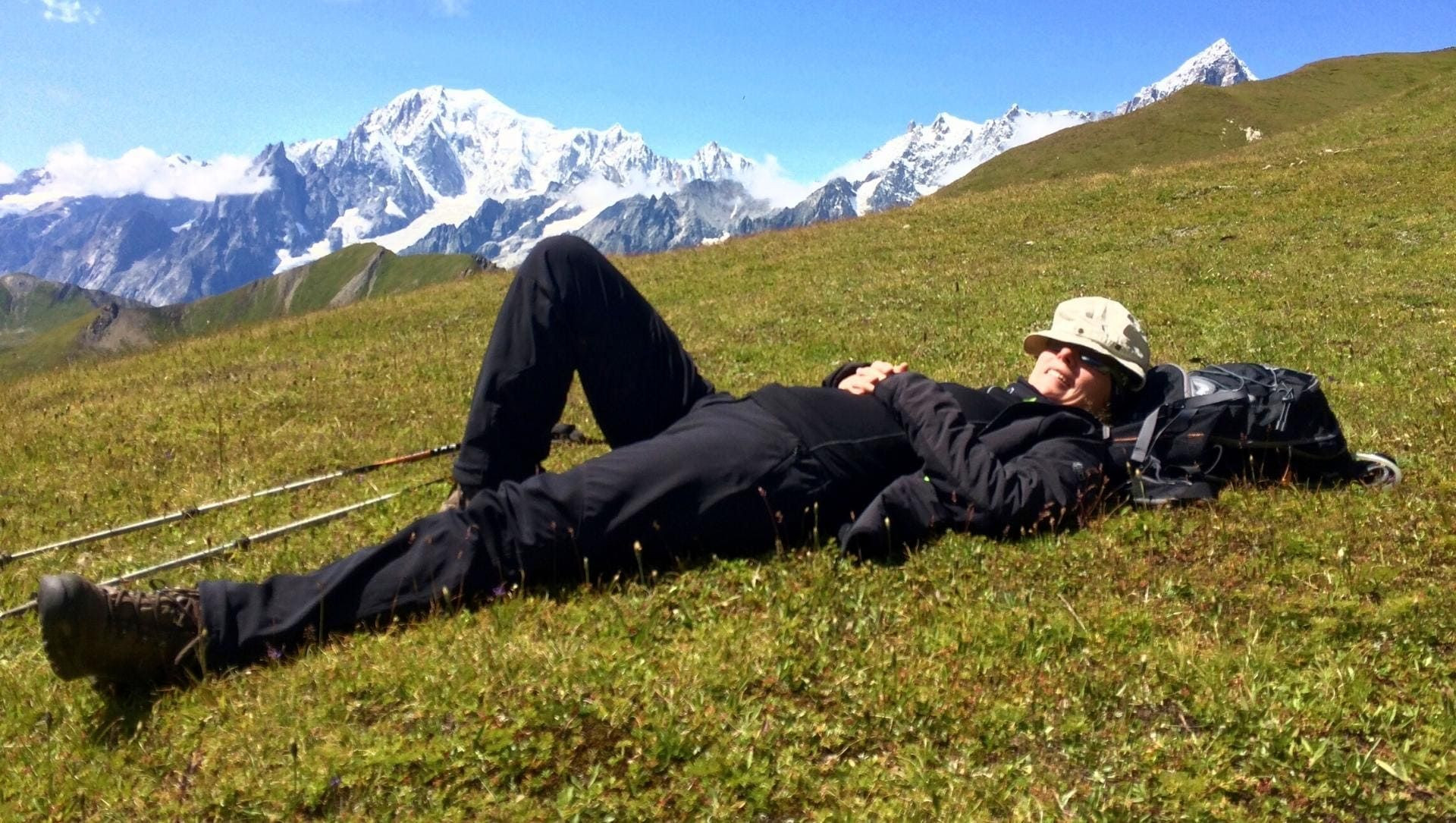 Randonneur allongé dans l'herbe face au massif du Mont-Blanc - Alpes - France