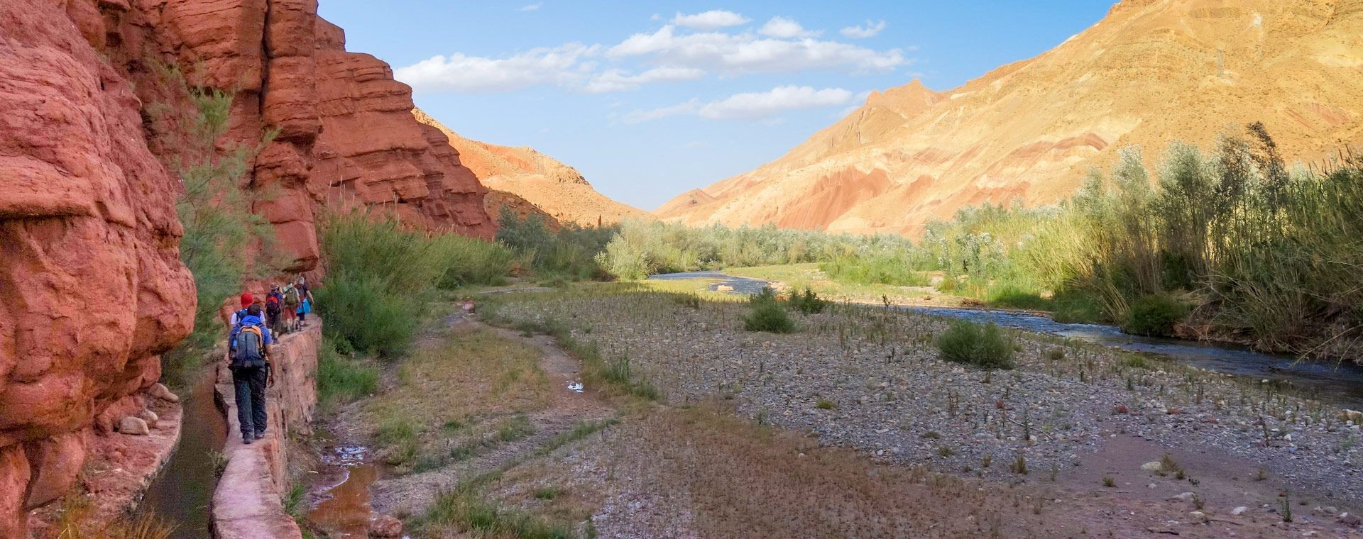 Randonneurs le long d'une séguia dans un canyon ocre - Vallée des Roses - Maroc