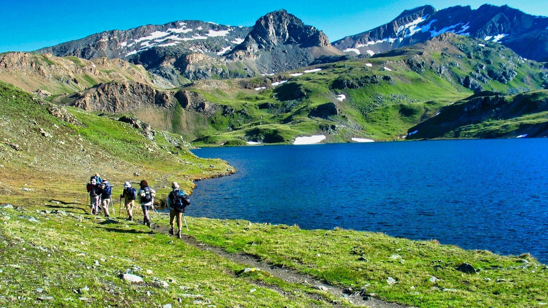 Randonneurs au bord d'un lac d'altitude sous des sommets enneigés - Grand Paradis - Vallée d'Aoste, Italie