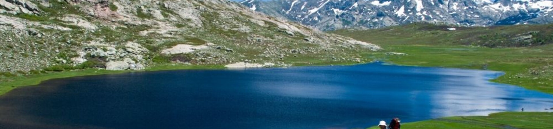 Hikers beside a mountain lake on the GR20 in Corsica