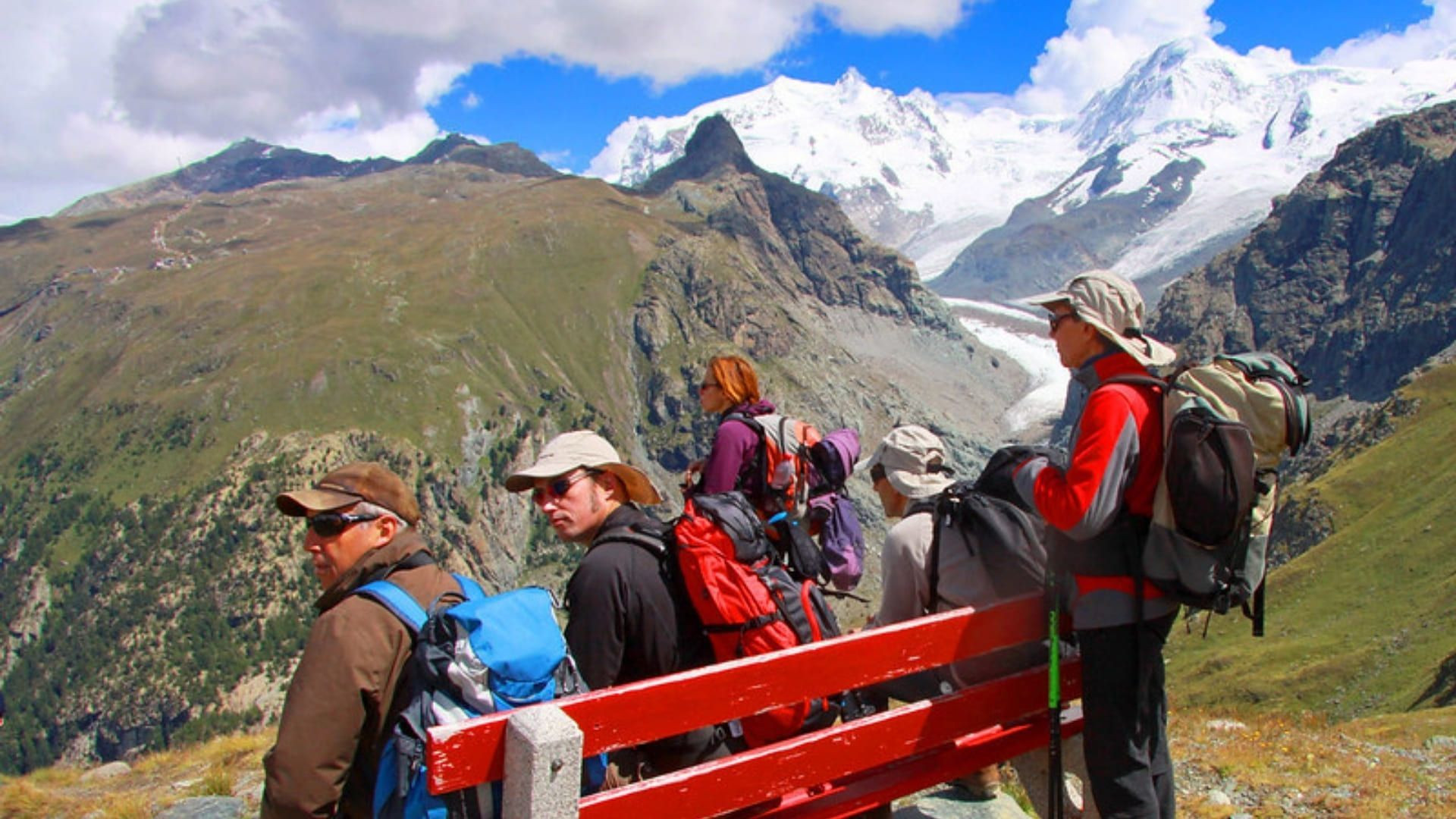 Randonneurs sur un banc rouge face au glacier - Tour du Mont Rose - Alpes