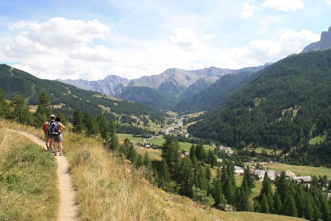 Randonneurs dominant une vallée et un village de montagne - Queyras - Alpes, France