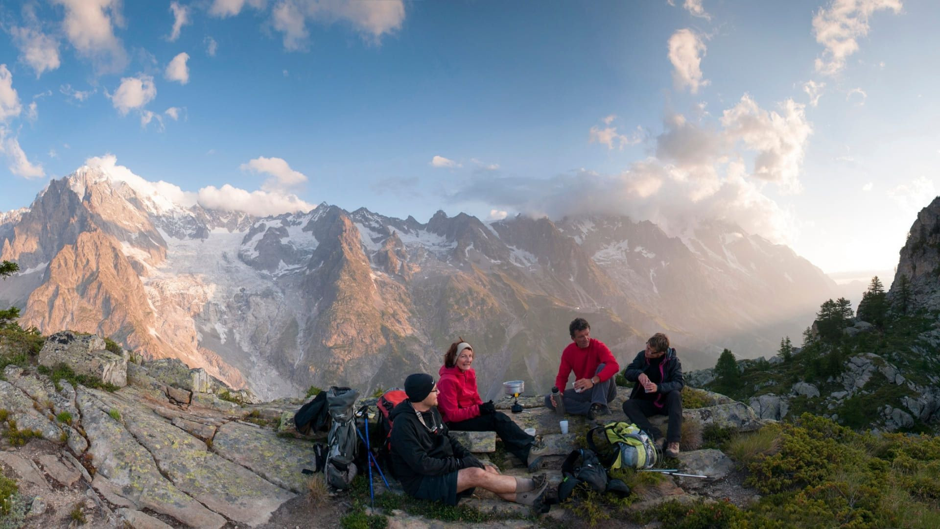 Randonneurs en pique-nique face au massif glaciaire au coucher du soleil - Alpes - France