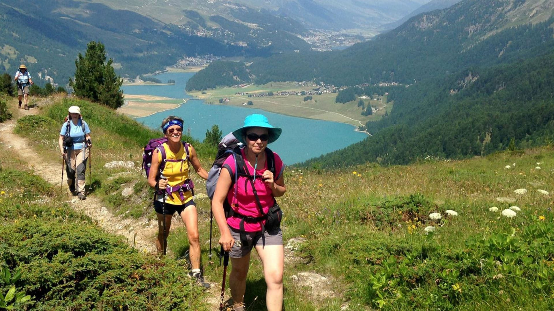 Randonneuses sur un sentier dominant un lac turquoise - Alpes