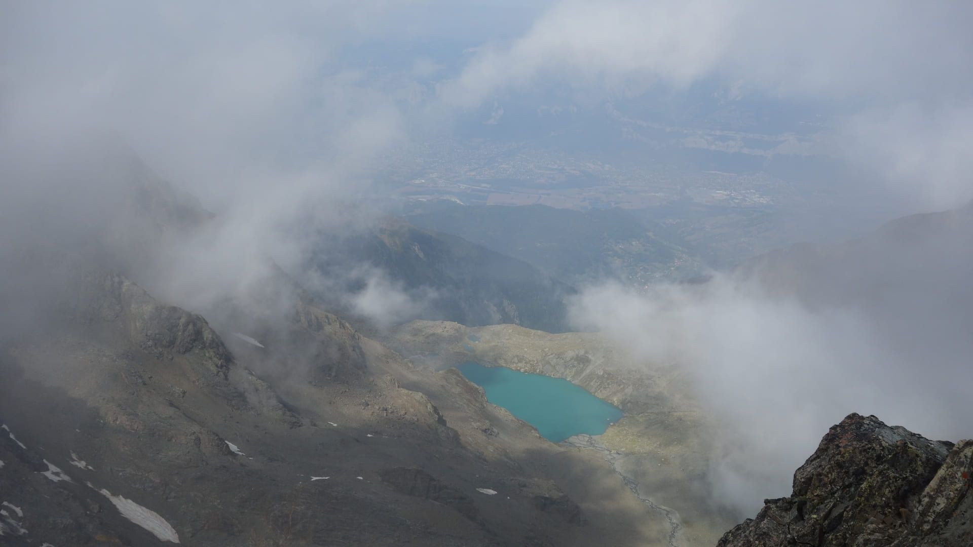 © Adrien Ozanon Lac turquoise vu du sommet dans les nuages - Belledonne - Alpes - France
