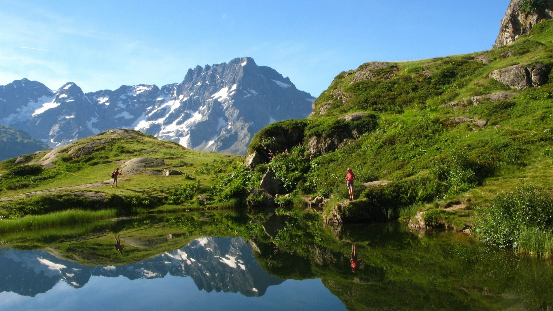 Randonneurs au lac alpin face aux sommets enneigés - Oisans - France