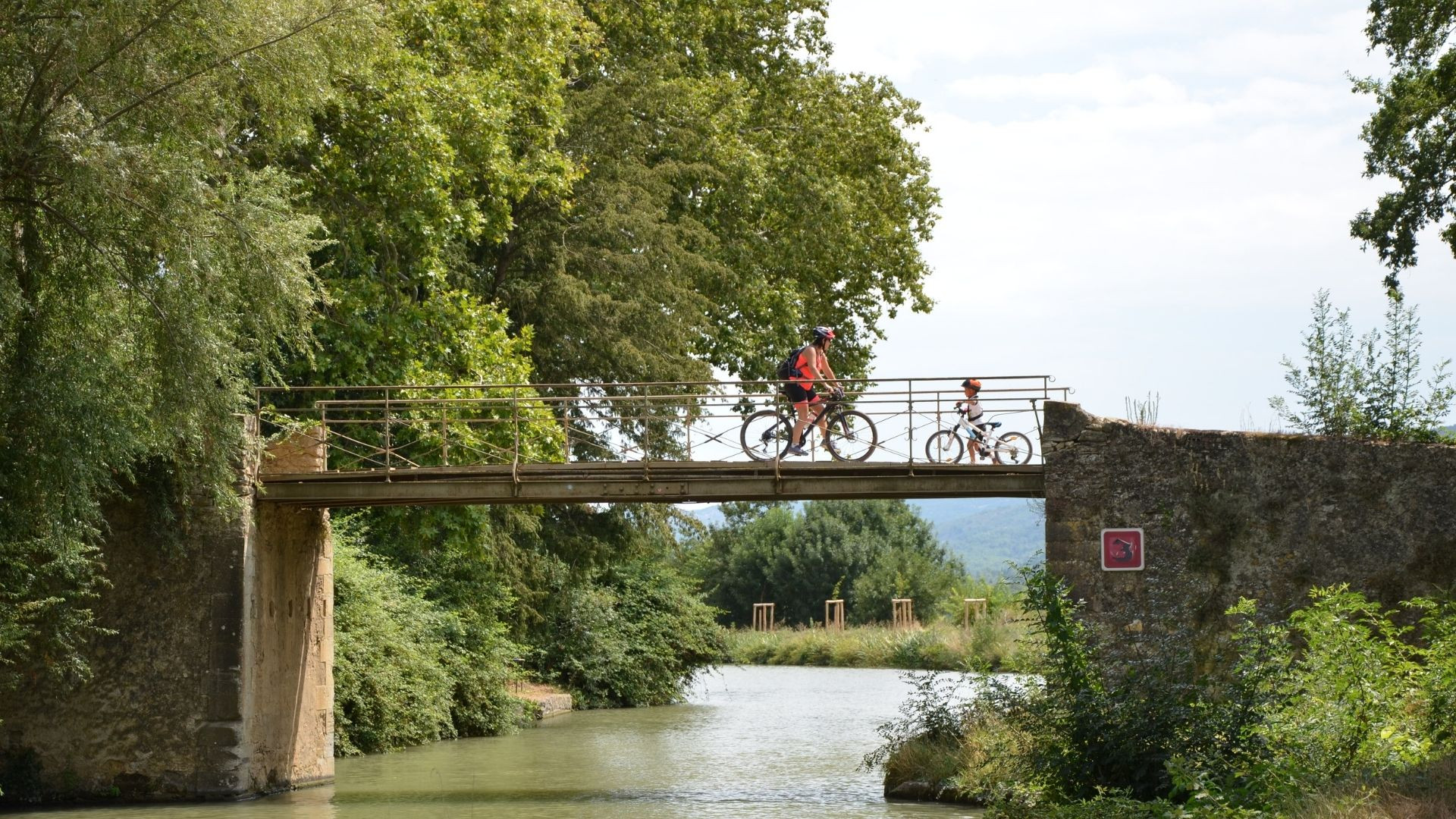 Cyclistes franchissant un pont sur le Canal du Midi - Occitanie - France