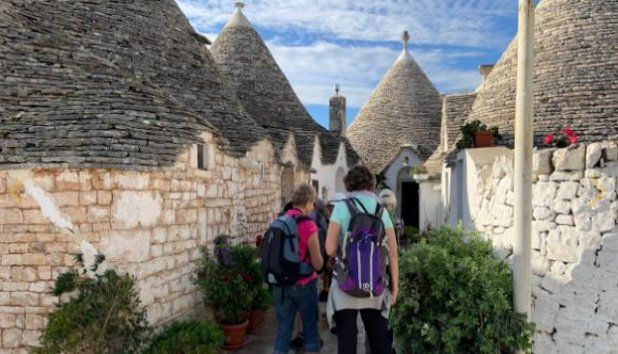 Randonneurs dans une ruelle de trulli en pierre sèche - Alberobello - Pouilles, Italie