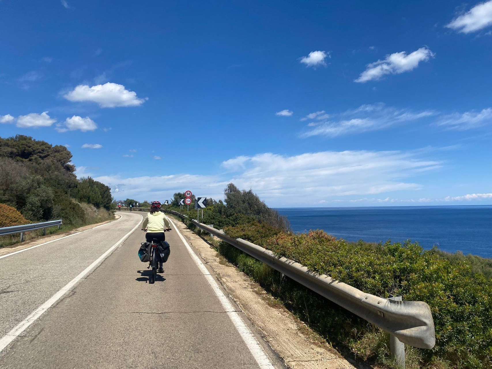 Cycliste chargé sur une route côtière - Méditerranée