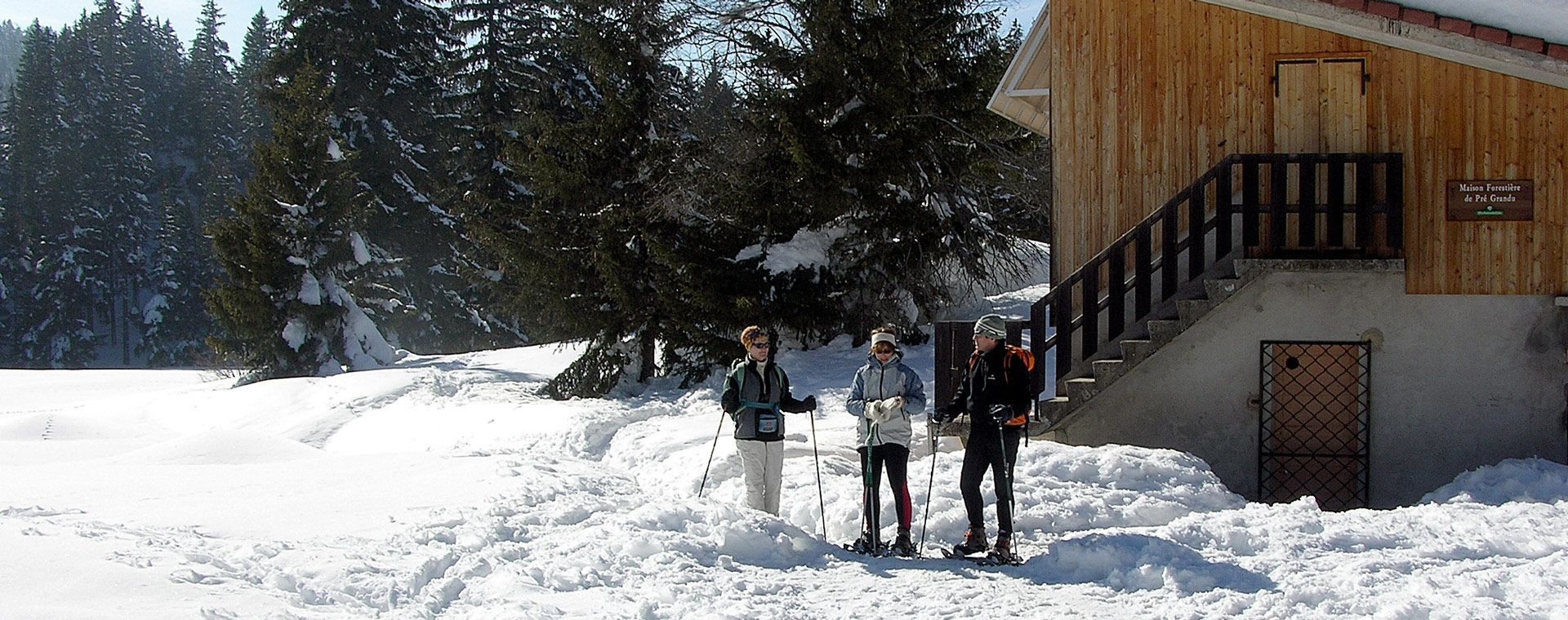 Randonneurs en raquettes près d'une maison forestière en hiver - France