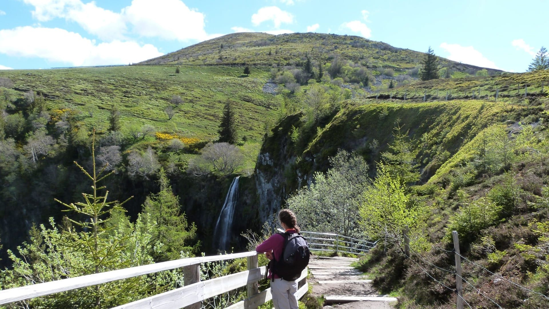 Randonneur face à une cascade et un volcan - Auvergne - France